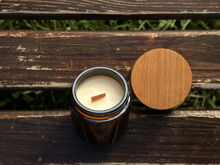 The natural soy candle with a wooden wick in a brown glass jar - obrazy, fototapety, plakaty
