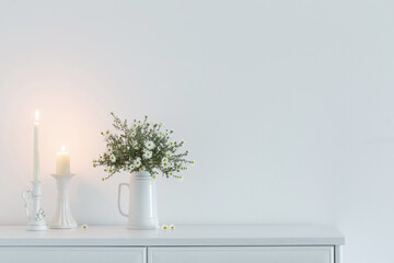 white flowers in white ceramic vase in white interior