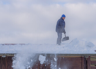 Cleaning snow from the roof. Man on the roof with shovel