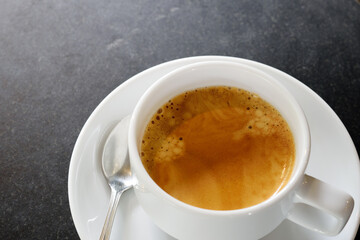 Hot coffee in a white cup in dark stone table