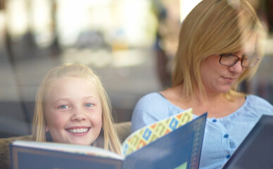 Reading, portrait and mother with child in bookshop with smile, learning and relax in knowledge. Storytelling, happy mom and girl in library together with story, fantasy books and education in window