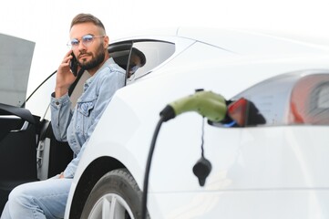Young stylish man is with electric car at daytime. The concept of green energy