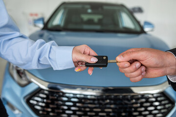 salesman car key handover from car sales to the owner at showroom