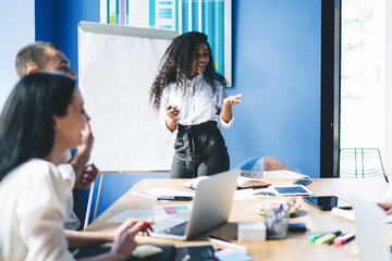 Content ethnic businesswoman doing presentation at flip chart