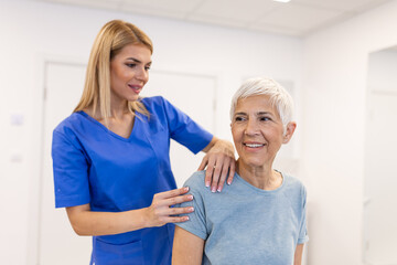 Woman doctor osteopath in medical uniform fixing senior woman patients shoulder and back joints in manual therapy clinic during visit. Professional osteopath during work with patient concept - obrazy, fototapety, plakaty