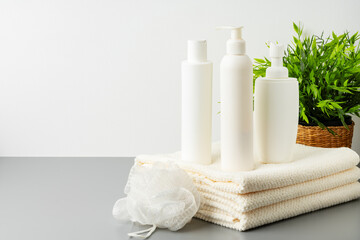 Fototapeta na wymiar Set of blank cosmetic bottles and towels on gray background