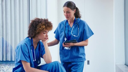 Female doctor wearing scrubs concerned about colleague suffering from stress and poor mental health In modern hospital - shot in slow motion