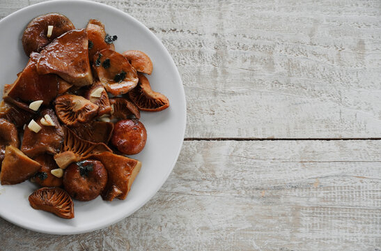 Edible mushrooms Rovellons or Niscalos. Plate of mushrooms and wooden table with copyspace. 