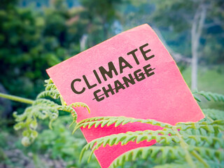 Awareness concept - climate change text on red paper with nature background.