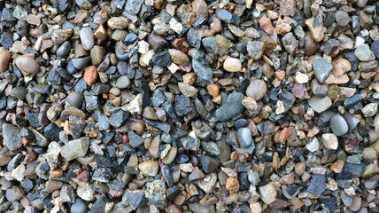 gray gravel with splashes of red and white as a natural texture, sharp wet pebbles top view as a finely textured background, screenings or crushed stone as a building industrial material