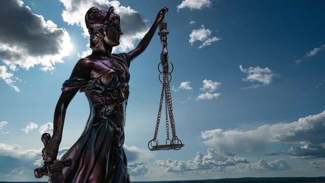the statue of justice turns against the backdrop of clouds moving across the blue sky. time lapse 4k.