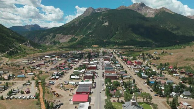 Aerial cinematic drone summer morning downtown Silverton Main Street southern Colorado Red Mountain Pass stunning lush green blue sky partly cloudy Rocky Mountains town forward movement