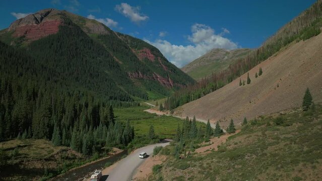 Aerial drone cinematic Ice Lake Basin trailhead driving camper van county road river summer early morning Silverton Telluride Colorado Rocky Mountains Aspen forest 14er peaks forward follow motion