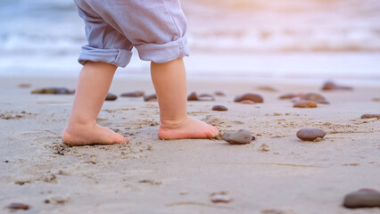 Little girl legs walk on beach. Toddler runs along beach creating delightful carefree scene, sunlight