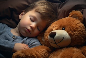 a cute little baby boy hugging a teddy bear while sleeping