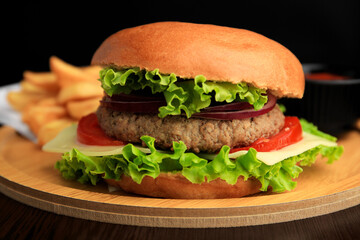 Tasty burger with vegetables, patty and cheese on wooden table, closeup