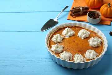 Delicious pumpkin pie with whipped cream on light blue wooden table, space for text