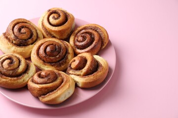 Many tasty cinnamon rolls on pink background, closeup. Space for text