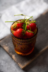 Red ripe strawberry in the glass on rustic background. Selective focus. Shallow depth of field.