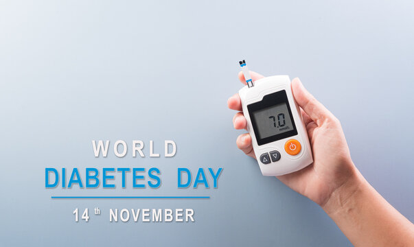 Healthcare and medical concept, Top view hand holding blood glucose meter test on pastel blue background. World Diabetes day, 14 November.