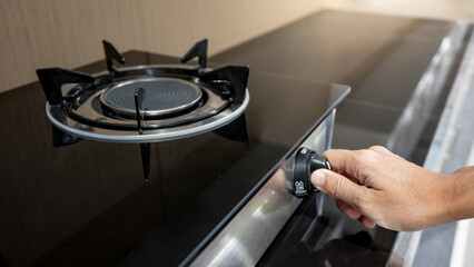 Male hand turning switch knob on modern gas stove in kitchen showroom. Cooking appliances in the...