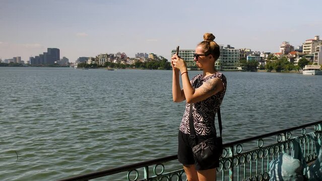 Young woman at Tay Ho Lake capturing images of the scenery around her