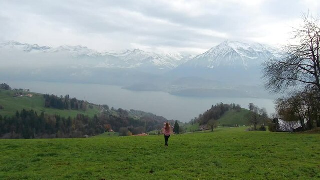 Cinematic aerial drone beautiful Swiss Alps countryside girl dancing in the fog hillside sounds of music scene Thun Bern Interlocken Switzerland mountainside circling slowly right movement