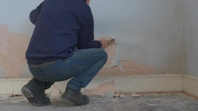 Adult working to scrap away blistered paint from interior wall. Home improvements