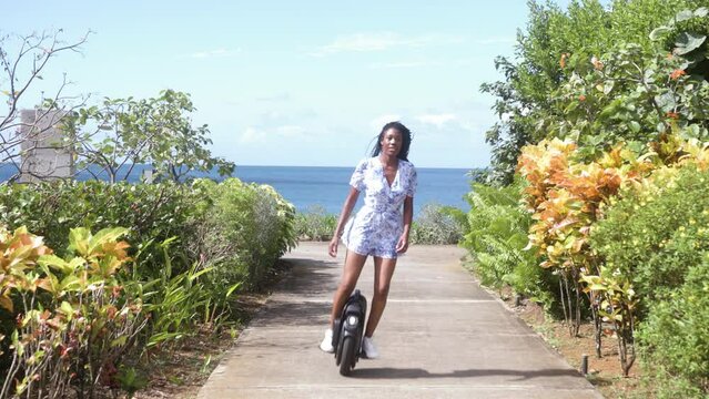 Woman's hair blows in the wind as she rides towards camera on monowheel electric unicycle
