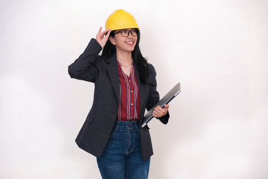Female engineer fixing her yellow safety hard hat and holding a laptop in hand