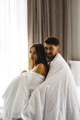 Obraz na płótnie Canvas Couple in love posing in blankets in a hotel room in the mountains. Concept for a vacation in the mountains