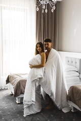 Couple in love posing in blankets in a hotel room in the mountains. Concept for a vacation in the mountains