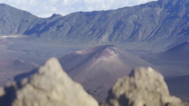 Cinematic shot with foreground elements of the volcanic cinder cone craters at the summit of Haleakala in Maui, Hawai'i. 4K HDR at 30 FPS