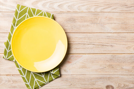 Top view on colored background empty round yellow plate on tablecloth for food. Empty dish on napkin with space for your design