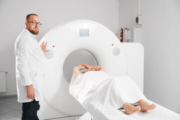 Medical computed tomography or MRI scanner. Male radiologist presses MRI button to examine female...