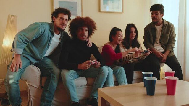 Group of friends encouraging two players who are playing console