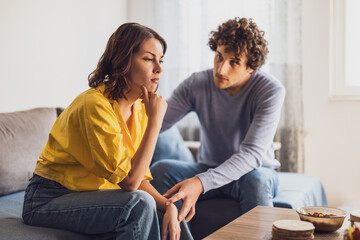 Man and woman are sitting at sofa and arguing. Relationship problems.