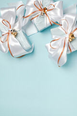Gift boxes wrapped in blue and silver paper with white and gold ribbon bows. Blue background, top view. Christmas and New Year gifts, Boxing Day.