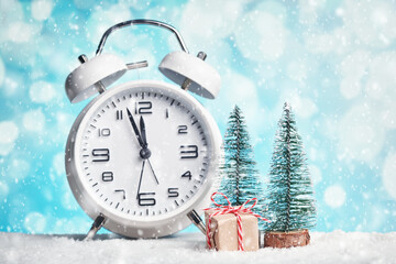 Small Christmas trees, a wrapped gift and the clock shows almost twelve o'clock. New Year celebration. - Powered by Adobe