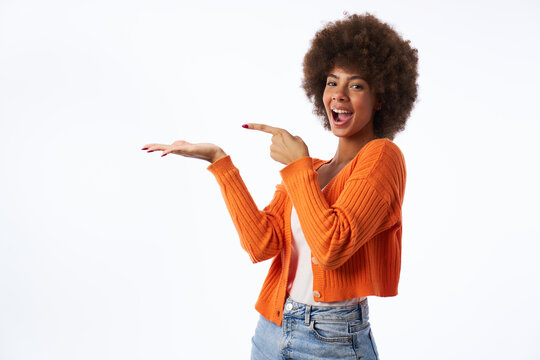 young latina woman with afro hair with surprised gesture points with hand isolated white background