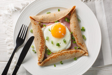 Breton galette, galette sarrasin, buckwheat crepe, with fried egg, cheese, ham closeup on the plate...