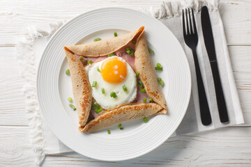 Galette complete Breton buckwheat pancake with egg cheese and ham closeup on the plate on the...