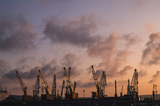 Bulgaria, Varna, Clouds over harbor cranes at dusk