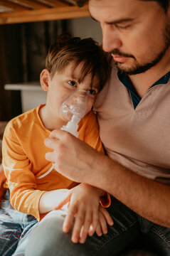 Man helping son with nebulizer at home