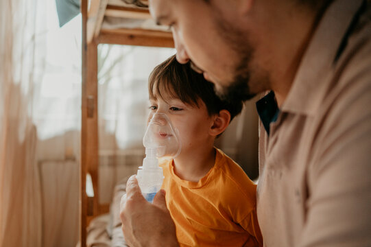 Man assisting son with nebulizer at home