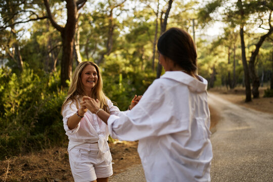 Happy mother holding hands with daughter enjoying at forest