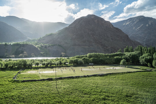 View of a football field next to the Pyandzh river on a high mountain plateau on the Pamir mountains of Tajikistan.