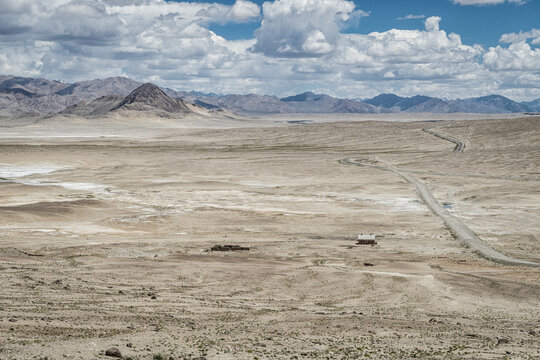 View of the Pamir highway with a lonely house on a high mountain deserted plateau in Tajikistan.