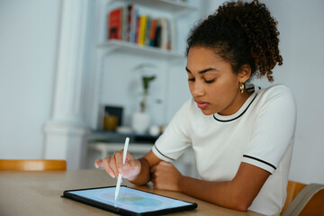 Student studying and writing on tablet PC at desk