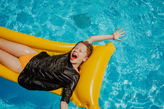 Happy girl screaming and lying on airbed in swimming pool
